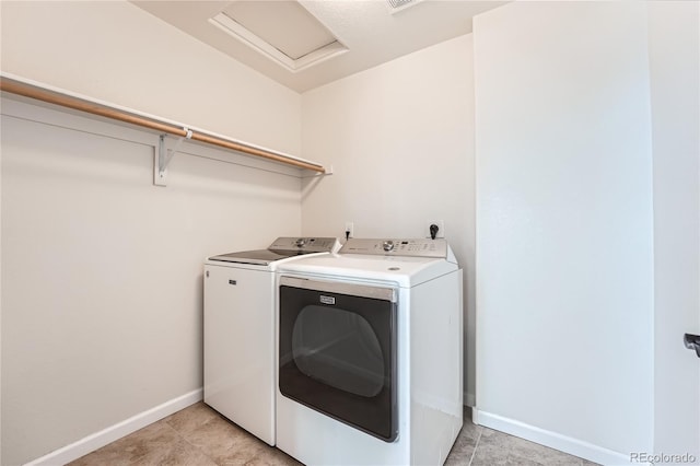 clothes washing area with laundry area, attic access, washing machine and dryer, and baseboards