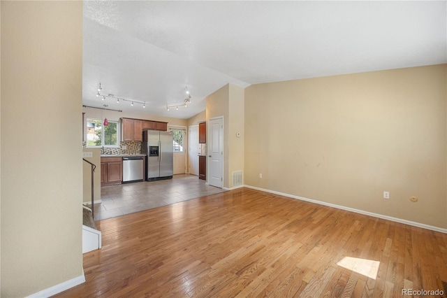 unfurnished living room featuring lofted ceiling and light hardwood / wood-style flooring