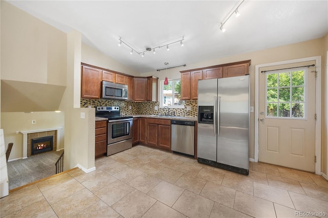 kitchen with pendant lighting, a healthy amount of sunlight, decorative backsplash, and stainless steel appliances