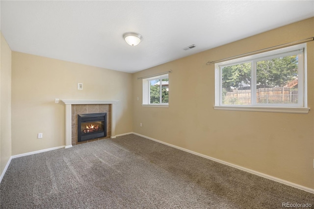 unfurnished living room featuring carpet floors and a tile fireplace