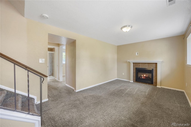 unfurnished living room with carpet floors and a tiled fireplace