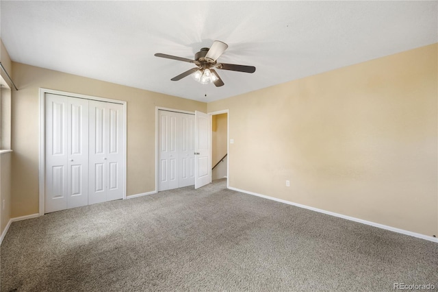 unfurnished bedroom with ceiling fan, multiple closets, and carpet floors