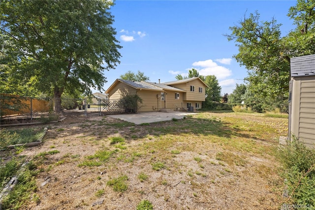 back of house with a lawn and a patio