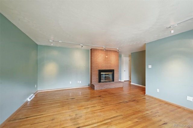 3784 Swadley St, Wheat Ridge, CO 80033 - unfurnished living room with track lighting, light wood-type flooring, and a brick fireplace