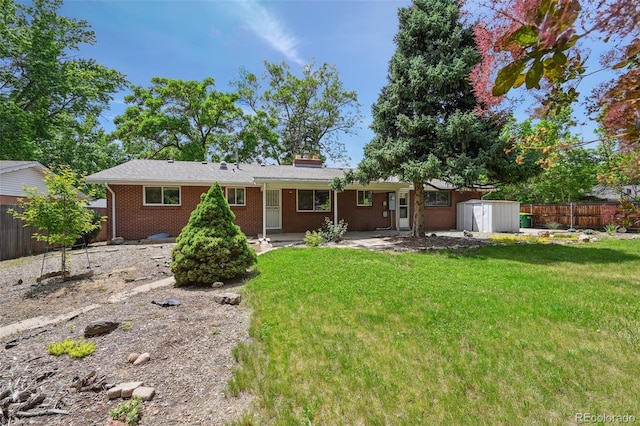 3784 Swadley St, Wheat Ridge, CO 80033 - back of house with a storage unit, a fenced backyard, brick siding, a chimney, and a patio