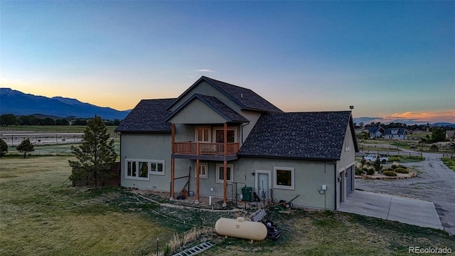 10757 Vista Farms Ct, Salida, CO 81201 - back of house at dusk with concrete driveway, stucco siding, a balcony, a garage, and a yard
