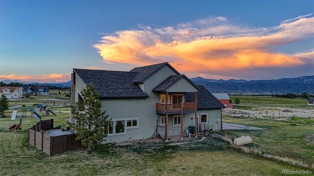 10757 Vista Farms Ct, Salida, CO 81201 - back of house at dusk with a balcony, a lawn, and stucco siding