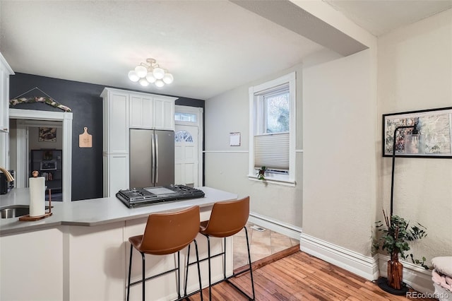 1612 N High St, Denver, CO 80218 - kitchen featuring stainless steel appliances, white cabinets, light wood finished floors, a breakfast bar area, and light countertops