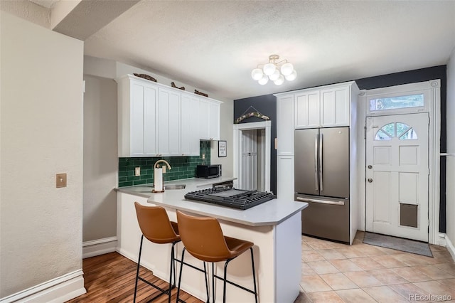 1612 N High St, Denver, CO 80218 - kitchen featuring stainless steel appliances, a peninsula, decorative backsplash, light countertops, and white cabinets