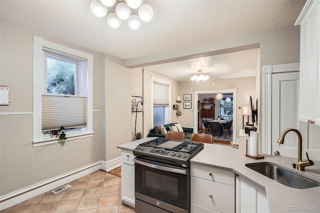 1612 N High St, Denver, CO 80218 - kitchen featuring a chandelier, gas range, light countertops, light tile patterned floors, and white cabinets