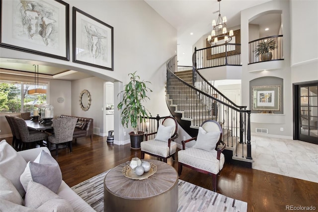 17490 W 67th Ave, Arvada, CO 80007 - living area with arched walkways, a towering ceiling, stairs, a chandelier, and baseboards