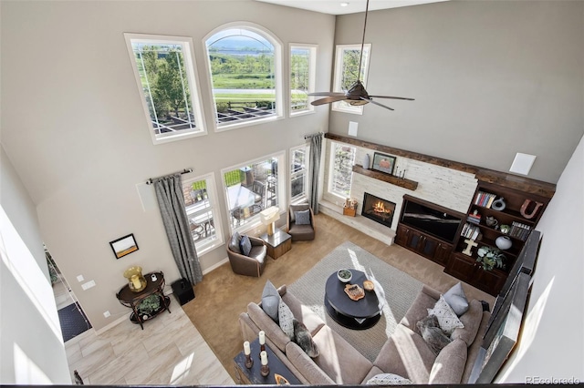 17490 W 67th Ave, Arvada, CO 80007 - living room with a high ceiling, a ceiling fan, a stone fireplace, and baseboards