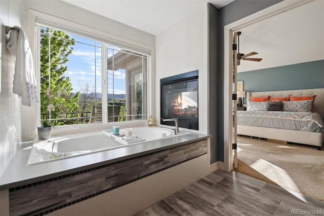17490 W 67th Ave, Arvada, CO 80007 - full bathroom with connected bathroom, a ceiling fan, a garden tub, and a glass covered fireplace