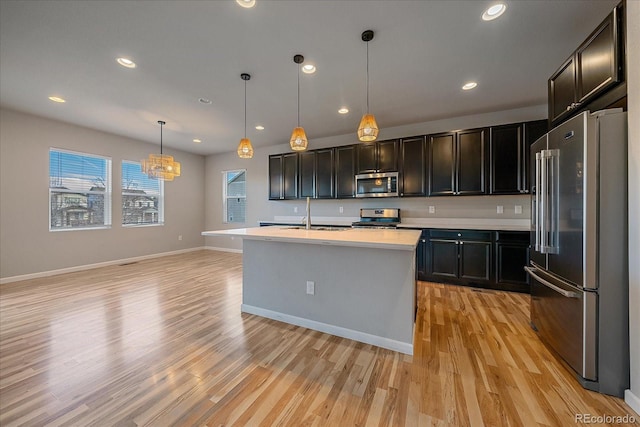 kitchen featuring pendant lighting, a center island with sink, sink, light hardwood / wood-style flooring, and stainless steel appliances