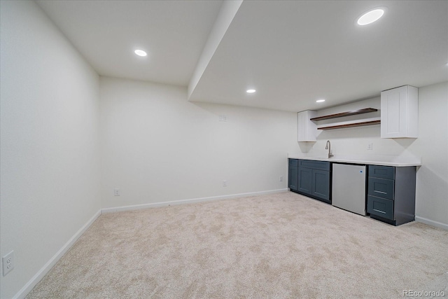 bar featuring stainless steel dishwasher, sink, white cabinetry, and light carpet