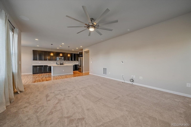 unfurnished living room featuring light carpet and ceiling fan