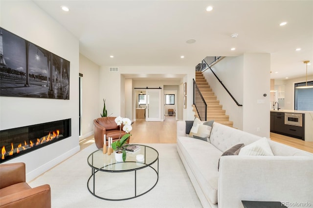 1462 S Vine St, Denver, CO 80210 - living area featuring stairway, recessed lighting, a barn door, light wood-style flooring, and a glass covered fireplace