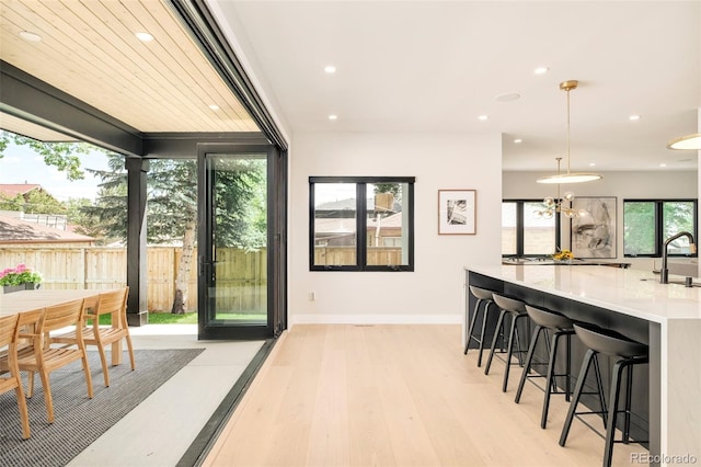 1462 S Vine St, Denver, CO 80210 - interior space featuring light wood-style floors, recessed lighting, light countertops, hanging light fixtures, and a kitchen breakfast bar