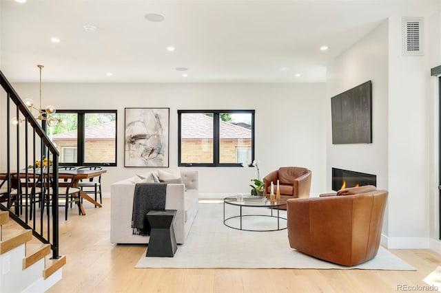 1462 S Vine St, Denver, CO 80210 - living area featuring stairs, light wood-style flooring, recessed lighting, a chandelier, and a glass covered fireplace