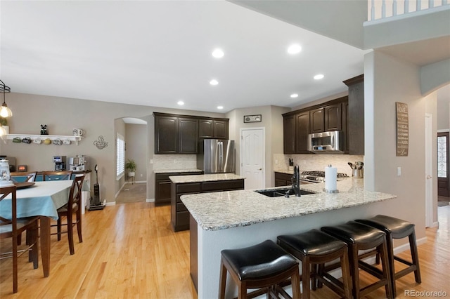 20460 Oakbrook Ln, Parker, CO 80138 - kitchen with arched walkways, stainless steel appliances, a sink, dark brown cabinetry, and recessed lighting