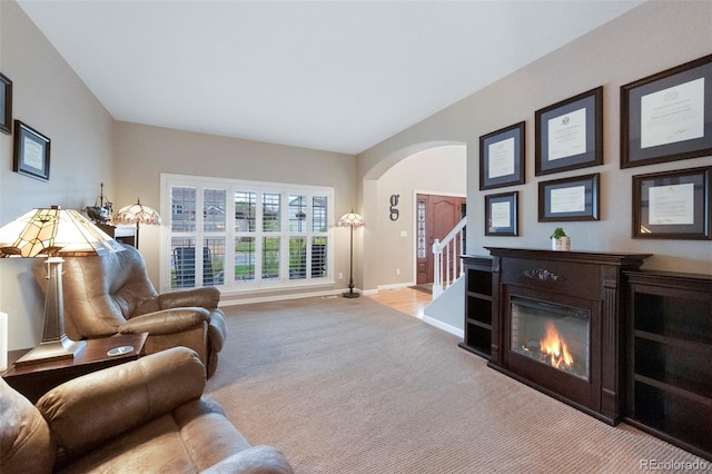 20460 Oakbrook Ln, Parker, CO 80138 - living area with arched walkways, carpet, baseboards, a glass covered fireplace, and stairs