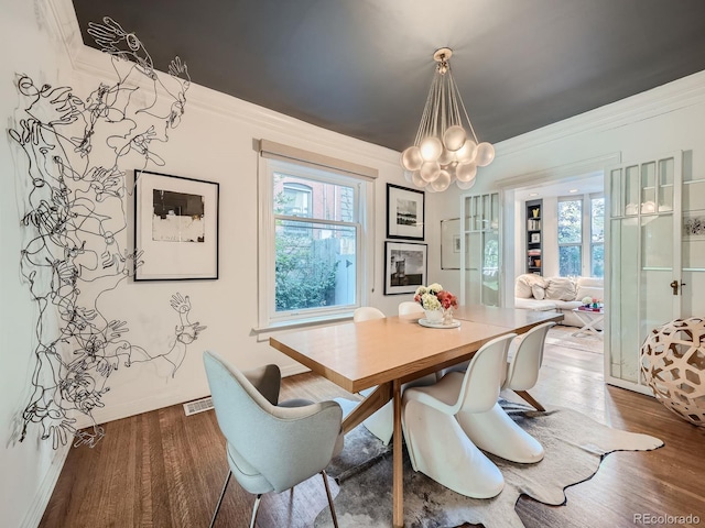 dining area featuring an inviting chandelier, crown molding, and dark hardwood / wood-style flooring