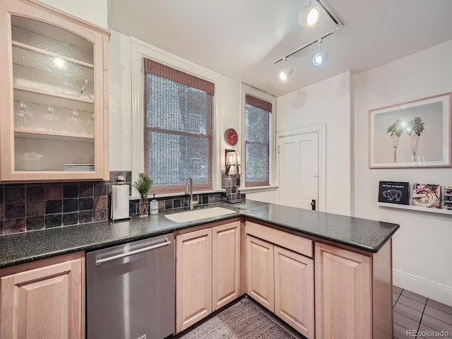 kitchen with dark tile patterned flooring, backsplash, light brown cabinetry, stainless steel dishwasher, and sink