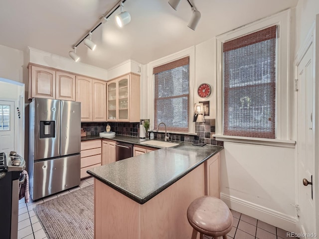 kitchen with tasteful backsplash, sink, appliances with stainless steel finishes, light tile patterned floors, and light brown cabinetry