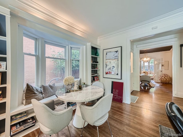 dining space with hardwood / wood-style flooring, built in shelves, an inviting chandelier, and plenty of natural light