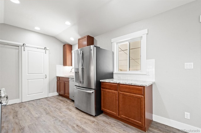 335 N 11th Ave, Brighton, CO 80601 - kitchen with appliances with stainless steel finishes, light wood finished floors, brown cabinets, vaulted ceiling, and baseboards