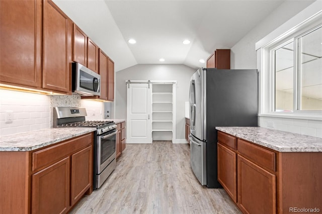335 N 11th Ave, Brighton, CO 80601 - kitchen featuring appliances with stainless steel finishes, vaulted ceiling, light wood finished floors, light countertops, and backsplash