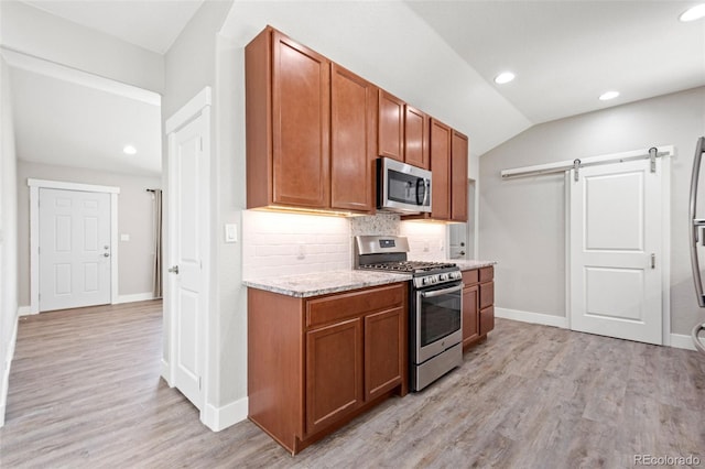 335 N 11th Ave, Brighton, CO 80601 - kitchen featuring stainless steel appliances, tasteful backsplash, baseboards, lofted ceiling, and a barn door