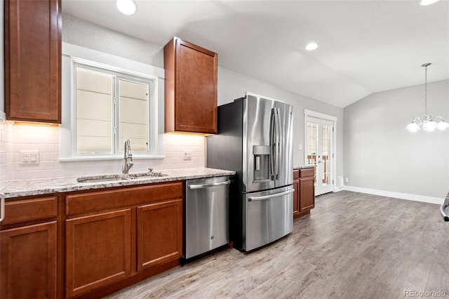 335 N 11th Ave, Brighton, CO 80601 - kitchen with appliances with stainless steel finishes, a sink, brown cabinetry, vaulted ceiling, and decorative backsplash