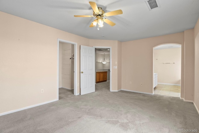 unfurnished bedroom with ceiling fan, light colored carpet, a spacious closet, and connected bathroom