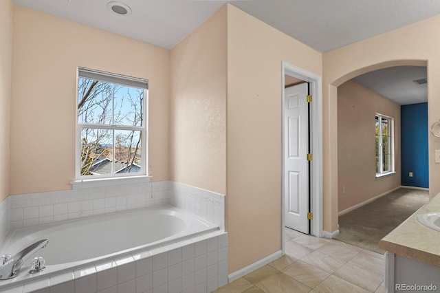 bathroom featuring tile patterned flooring, vanity, and tiled tub