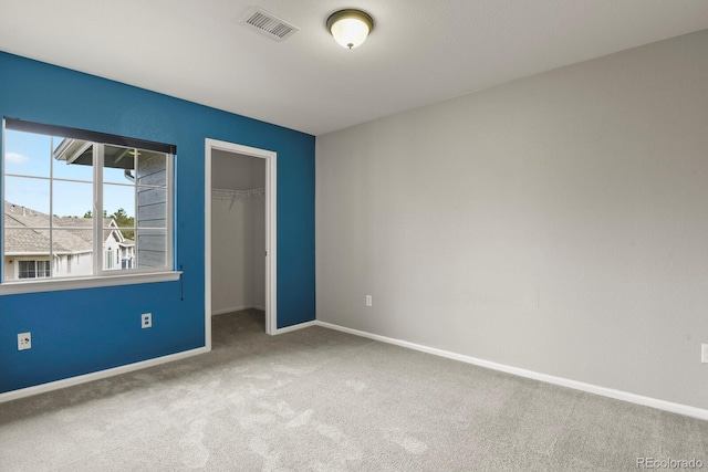 unfurnished bedroom with carpet, a spacious closet, and a closet