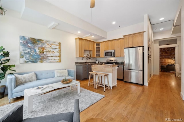 living room featuring brick wall, light wood-type flooring, and sink