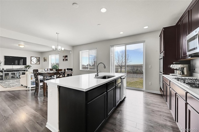 kitchen with dark wood-type flooring, a center island with sink, a healthy amount of sunlight, and sink