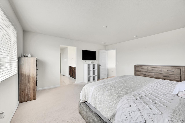 bedroom featuring light carpet and ensuite bathroom