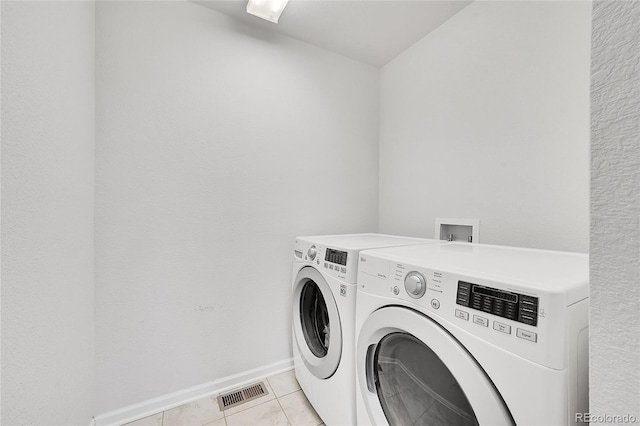 laundry area with washer and clothes dryer and light tile patterned floors