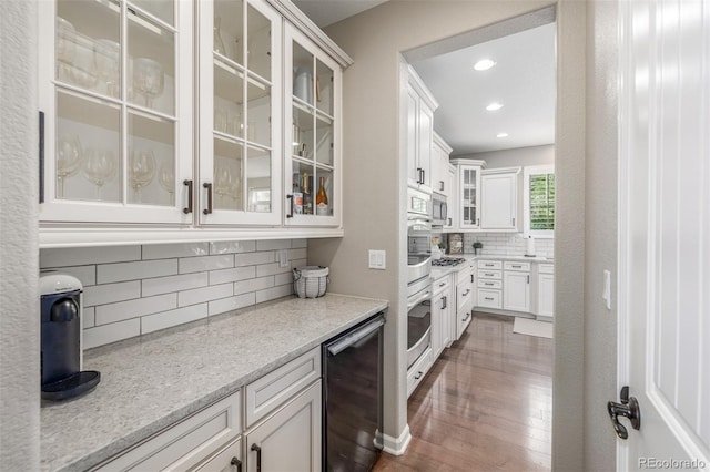 14258 Greenfield Loop, Parker, CO 80134 - kitchen featuring decorative backsplash, dark wood-style floors, white cabinetry, stainless steel microwave, and glass insert cabinets