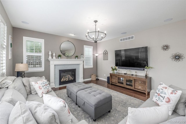 14258 Greenfield Loop, Parker, CO 80134 - living area featuring wood finished floors, a chandelier, a brick fireplace, and baseboards