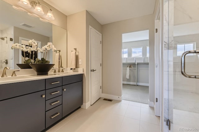 bathroom with a shower with door, vanity, and tile patterned floors