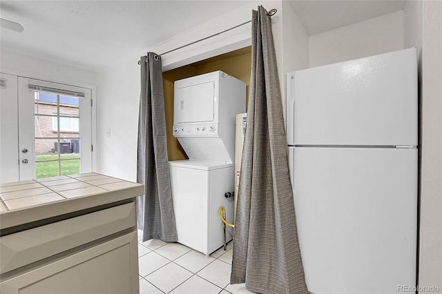 laundry area with light tile patterned floors and stacked washer and dryer