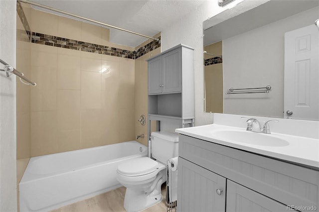 full bathroom with tiled shower / bath combo, wood-type flooring, a textured ceiling, toilet, and vanity