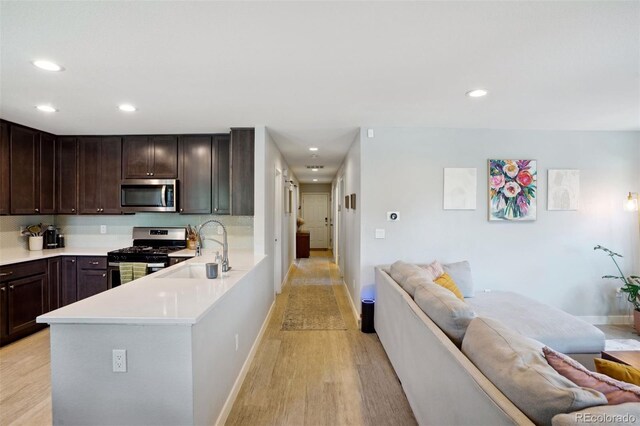 4080 Adams St, Denver, CO 80216 - kitchen featuring appliances with stainless steel finishes, a sink, open floor plan, light wood-type flooring, and recessed lighting
