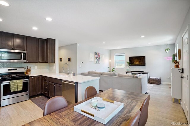 4080 Adams St, Denver, CO 80216 - kitchen with stainless steel appliances, a sink, dark brown cabinetry, light countertops, and open floor plan