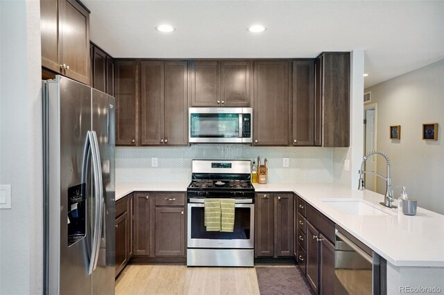 4080 Adams St, Denver, CO 80216 - kitchen with appliances with stainless steel finishes, a sink, a peninsula, dark brown cabinets, and light countertops