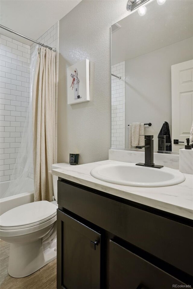 4080 Adams St, Denver, CO 80216 - bathroom with vanity, toilet, shower / tub combo with curtain, and wood finished floors