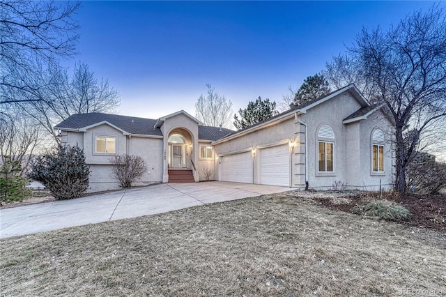 ranch-style home featuring stucco siding, an attached garage, and driveway